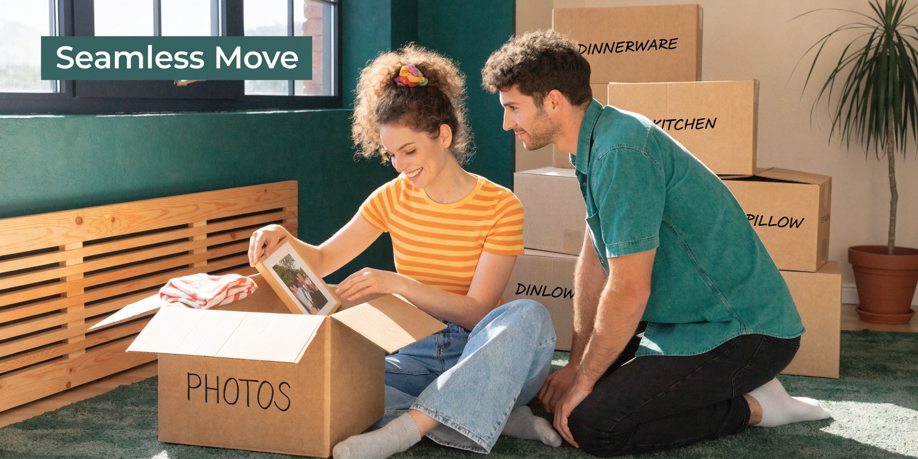 A happy young couple unpacking personal belongings from a box labeled photos in their new home.