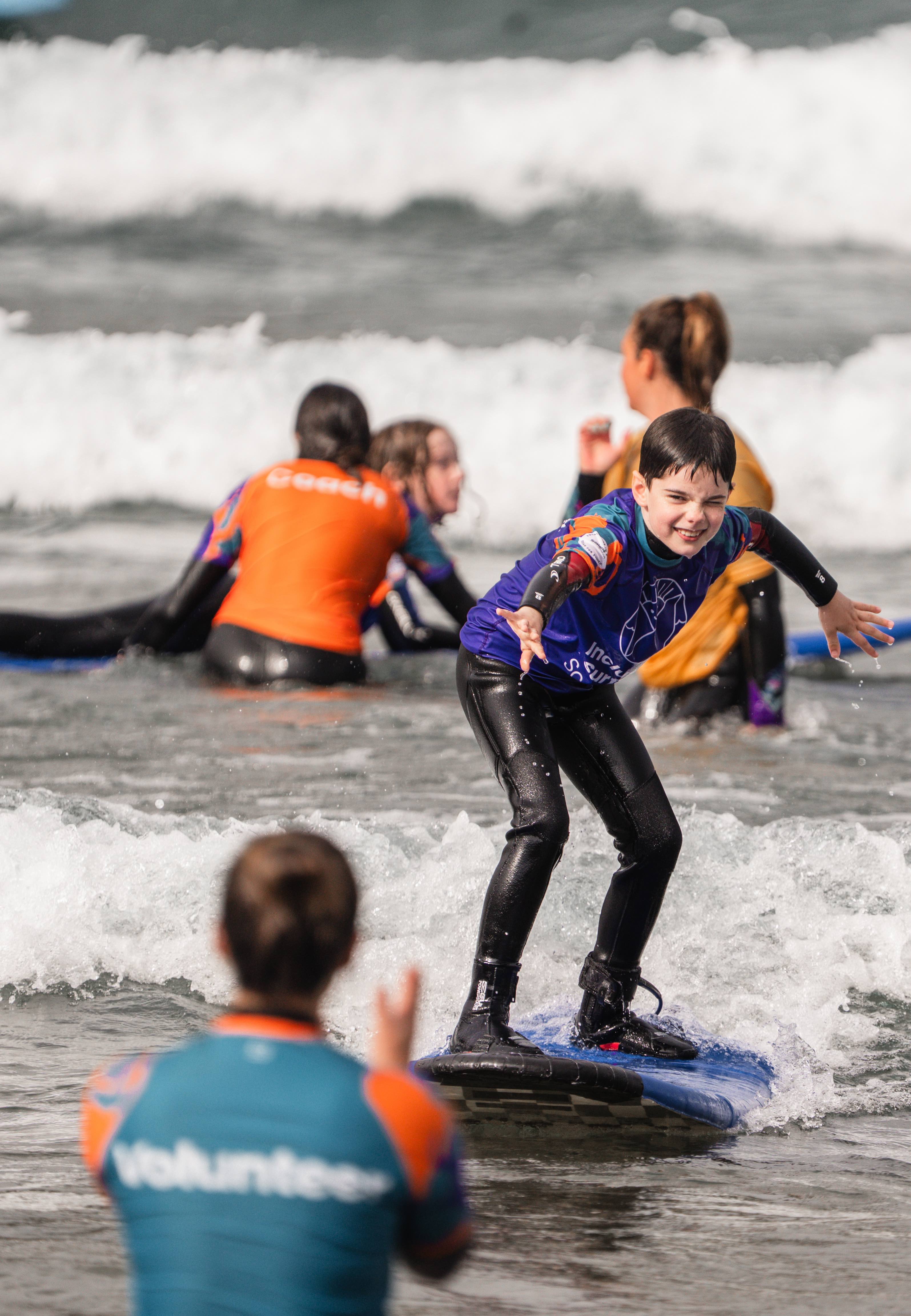 Volunteer clapping as a surfer rides towards them