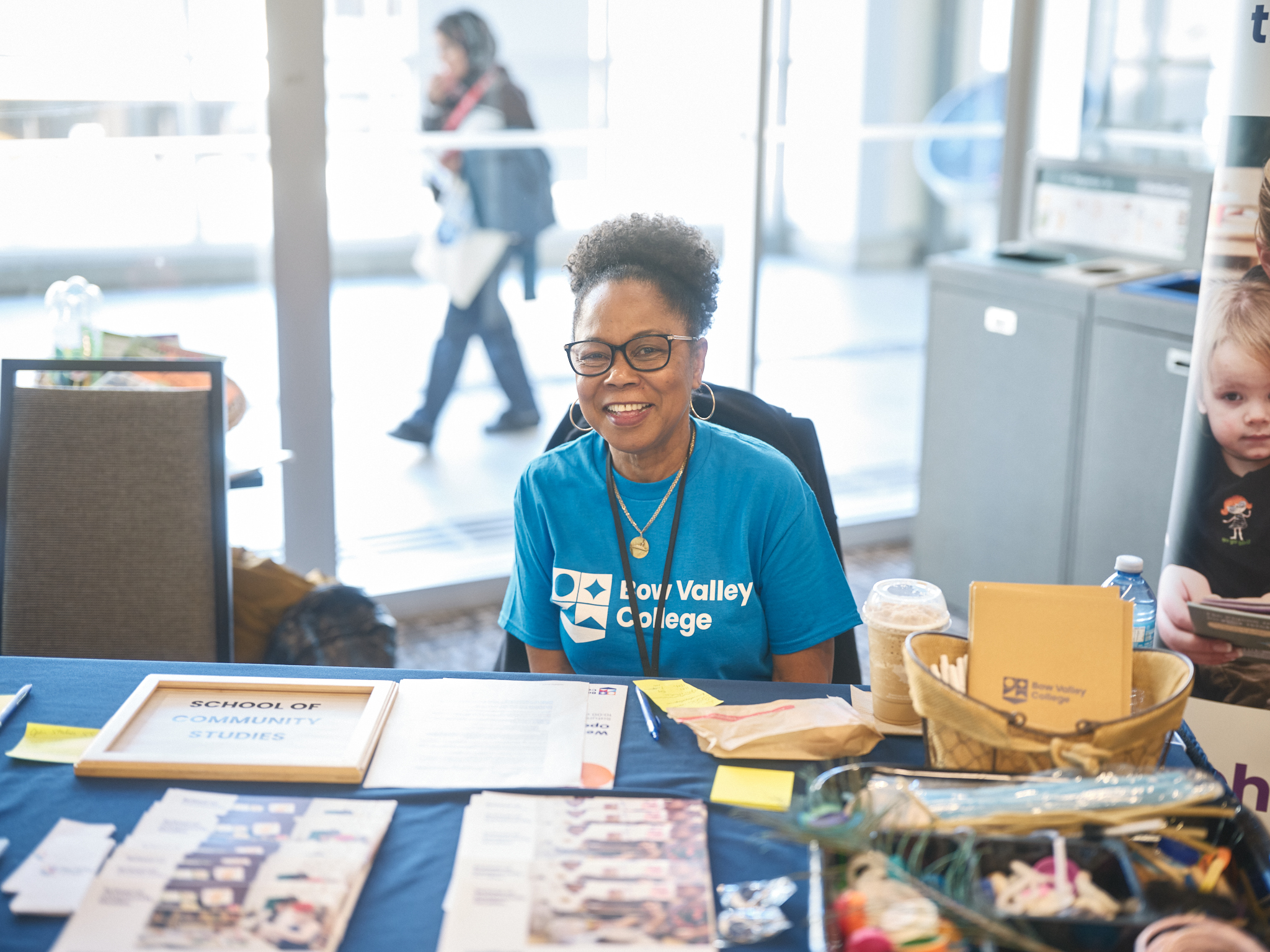 A Bow Valley College staff member smiling at a table at the Open House event.