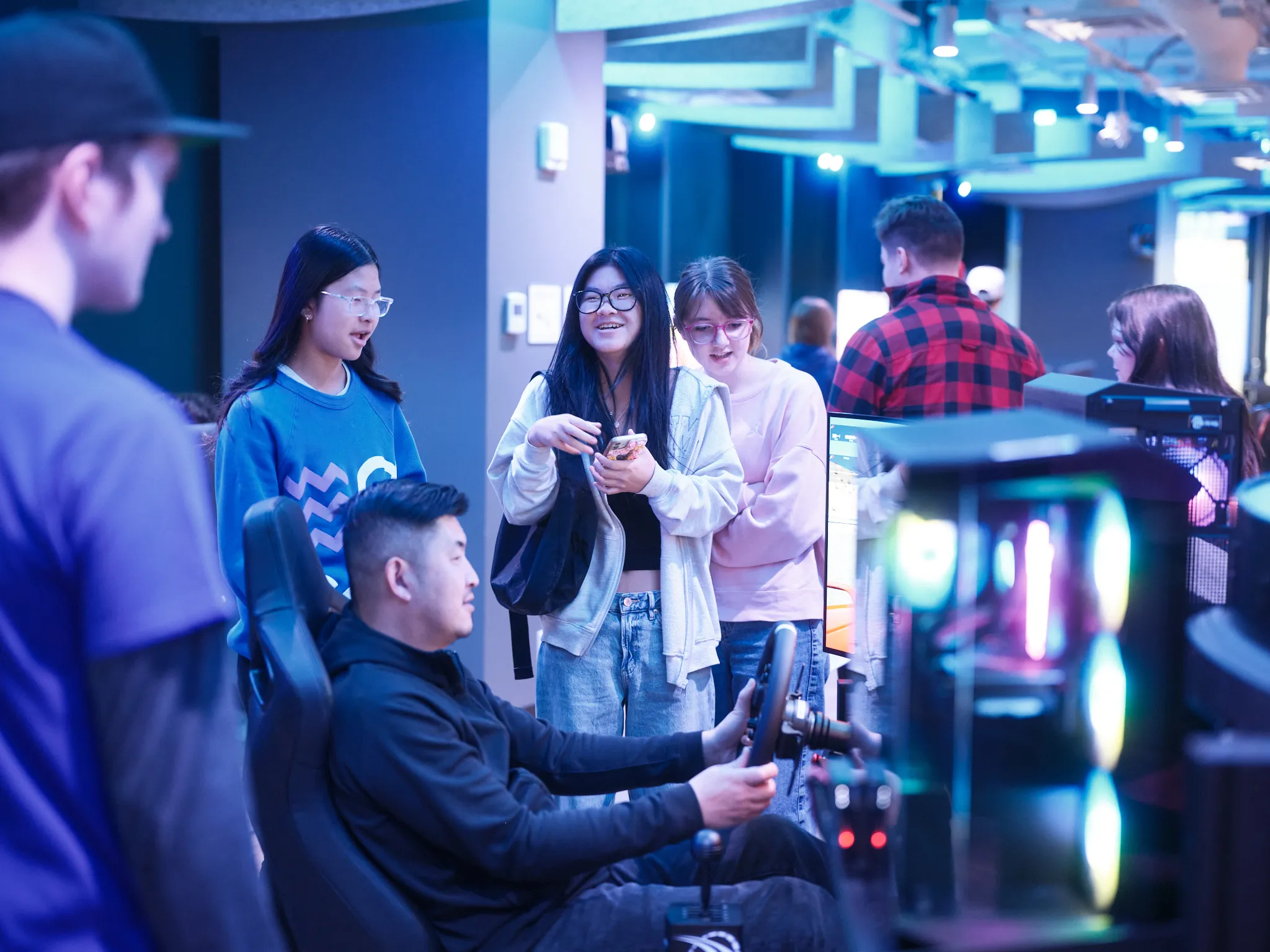 Prospective students watching someone use the gaming simulator at Bow Valley College's ESports arena.