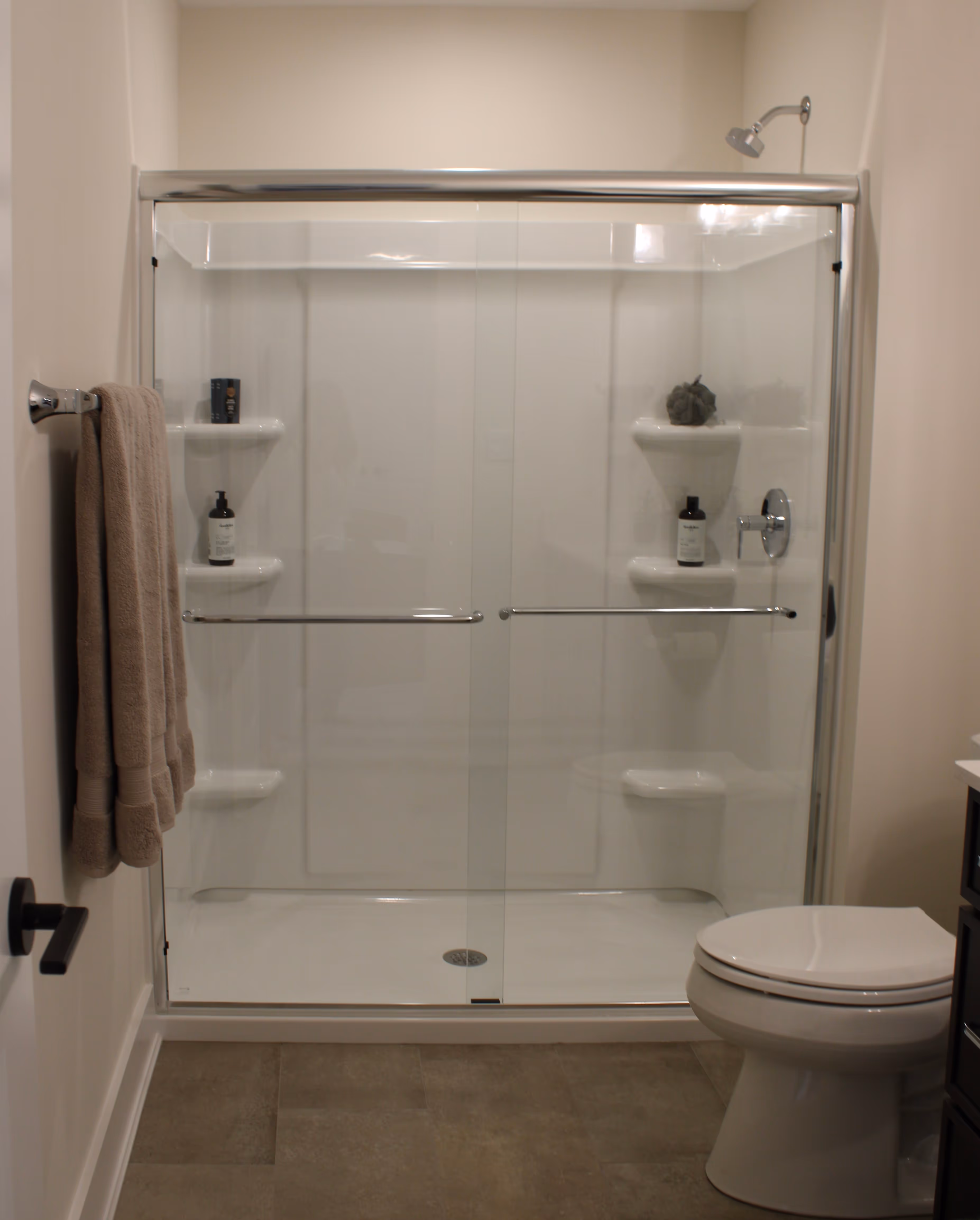 Modern bathroom with a glass-enclosed shower featuring built-in shelves and a white toilet nearby.