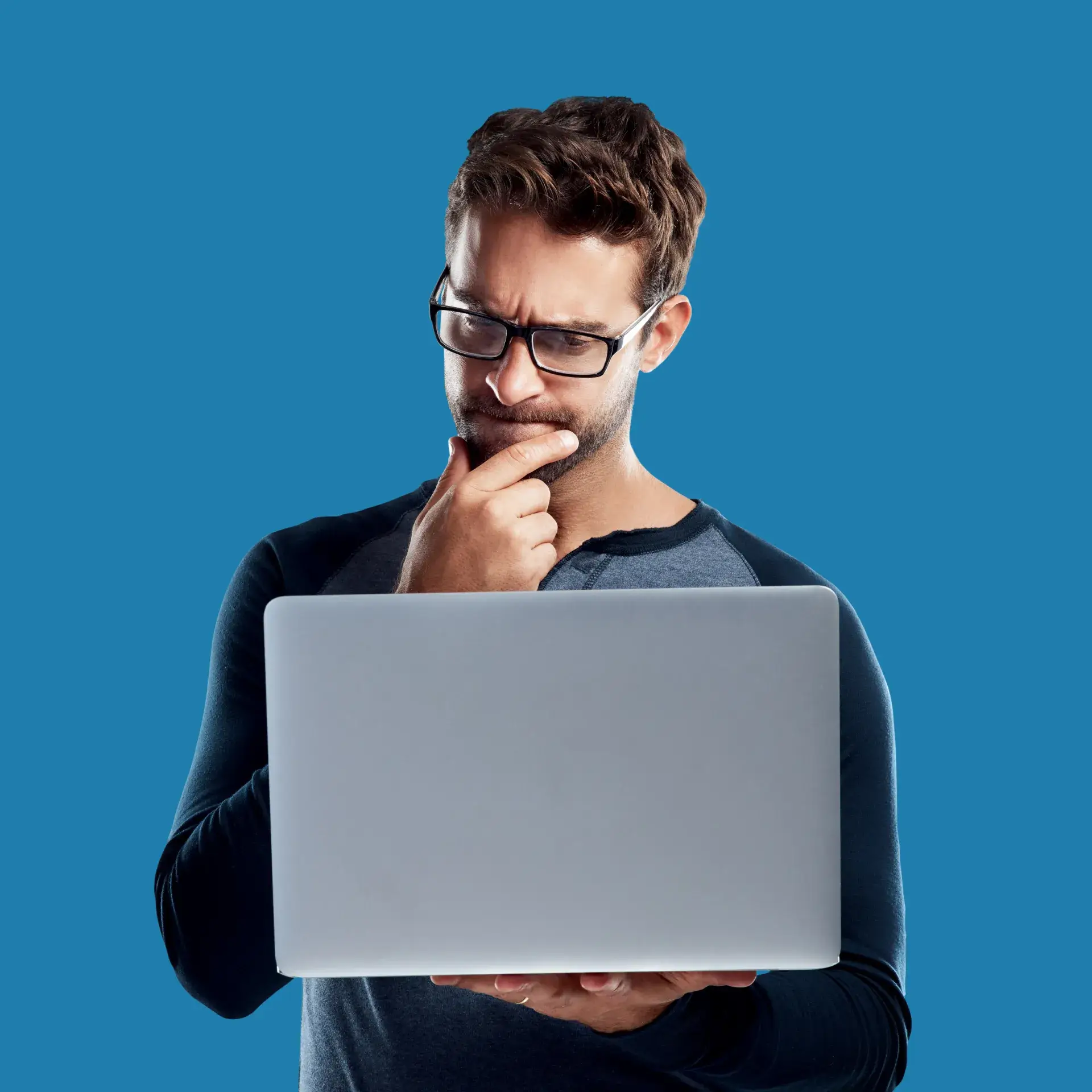 A man wearing glasses looking at a laptop.