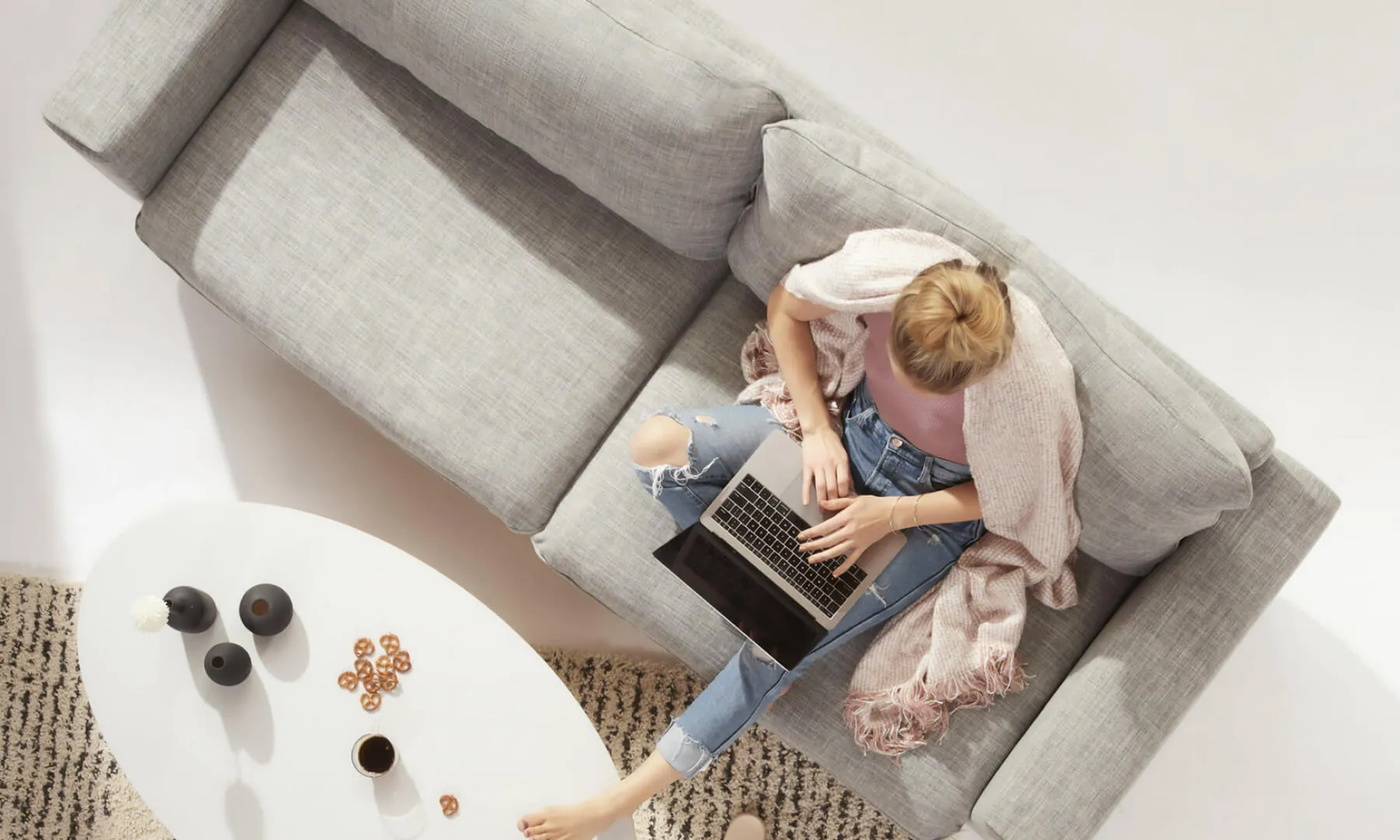 Stockphoto einer Frau, die mit Laptop auf einer Couch sitzt