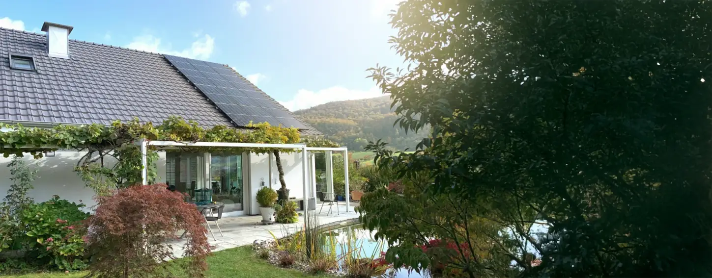 Einfamilienhaus mit einer Photovoltaikanlage auf dem Dach und schön grünem Garten