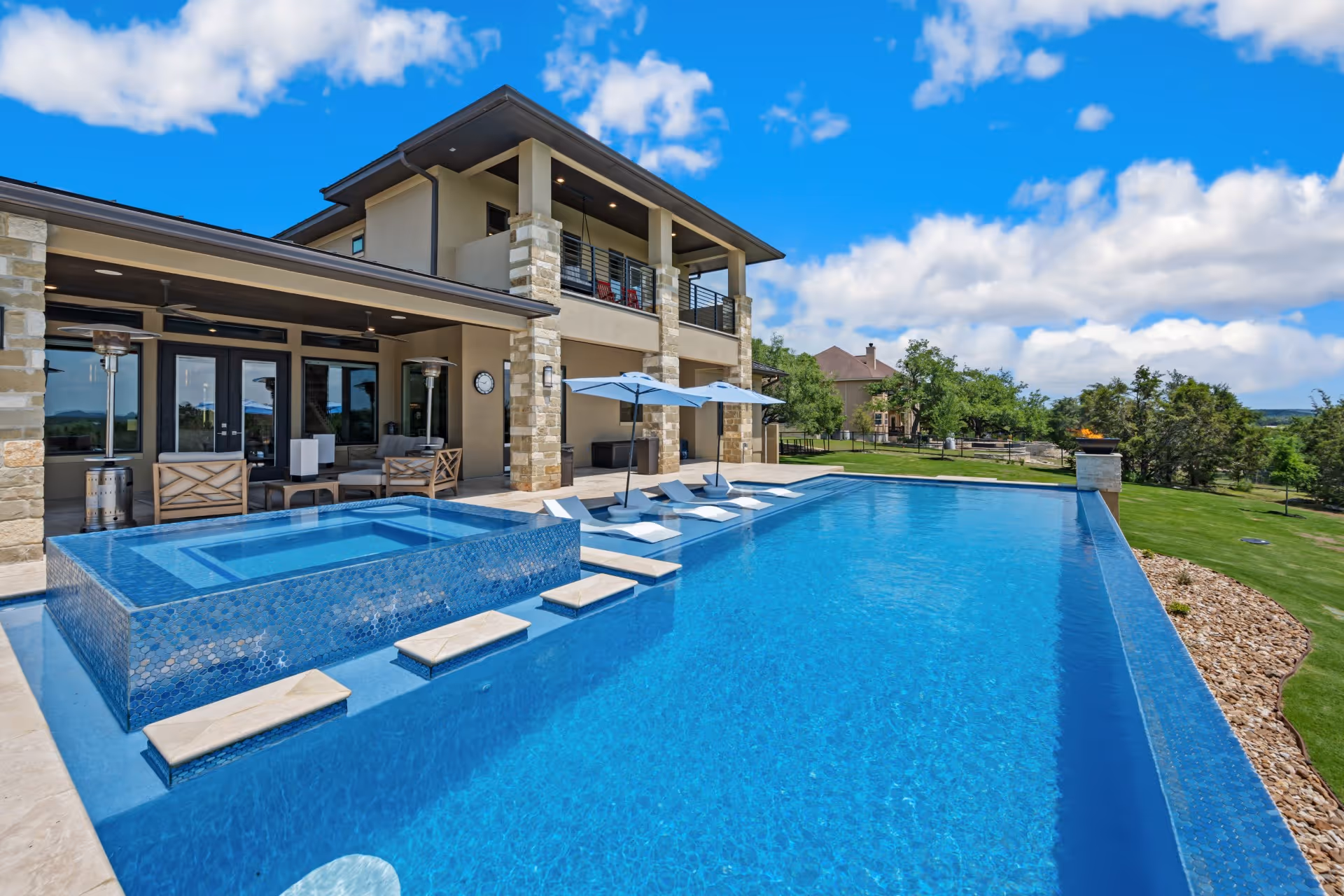 Luxurious modern pool in Bee Cave, Texas featuring a hot tub and floating steps