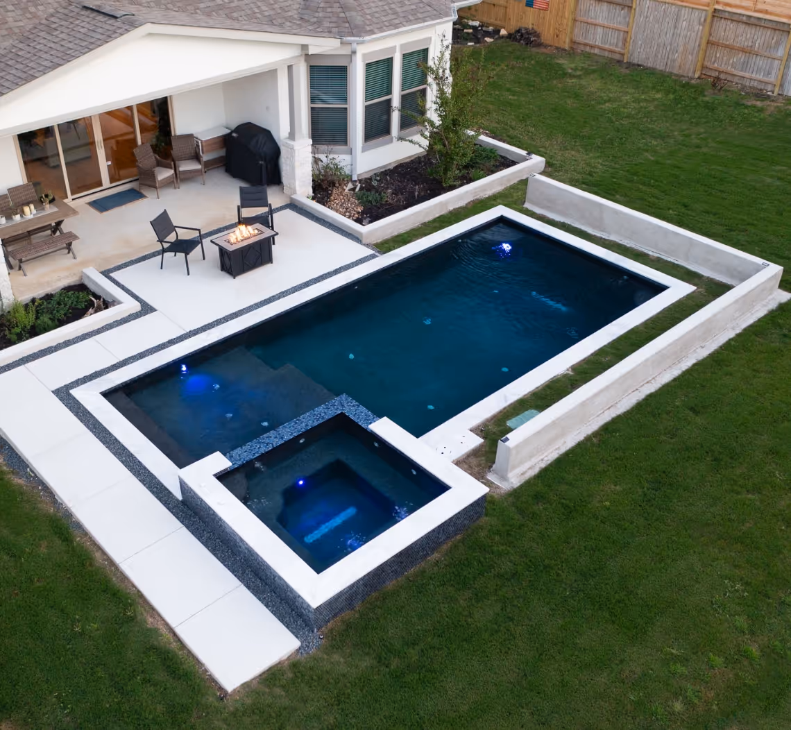 New pool build in Bee Cave, Texas featuring a sleek modern design, integrated spa, and contemporary backyard landscaping.