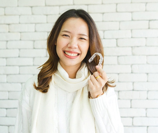 Patient holding clear aligners for discreet teeth straightening in Minnetonka MN.