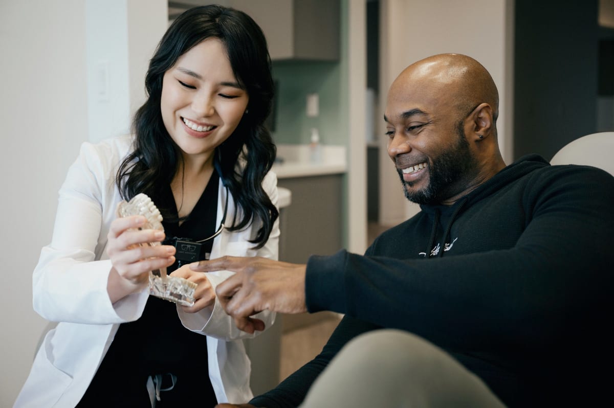 Female dentist in white coat smiling with male patient in dental office