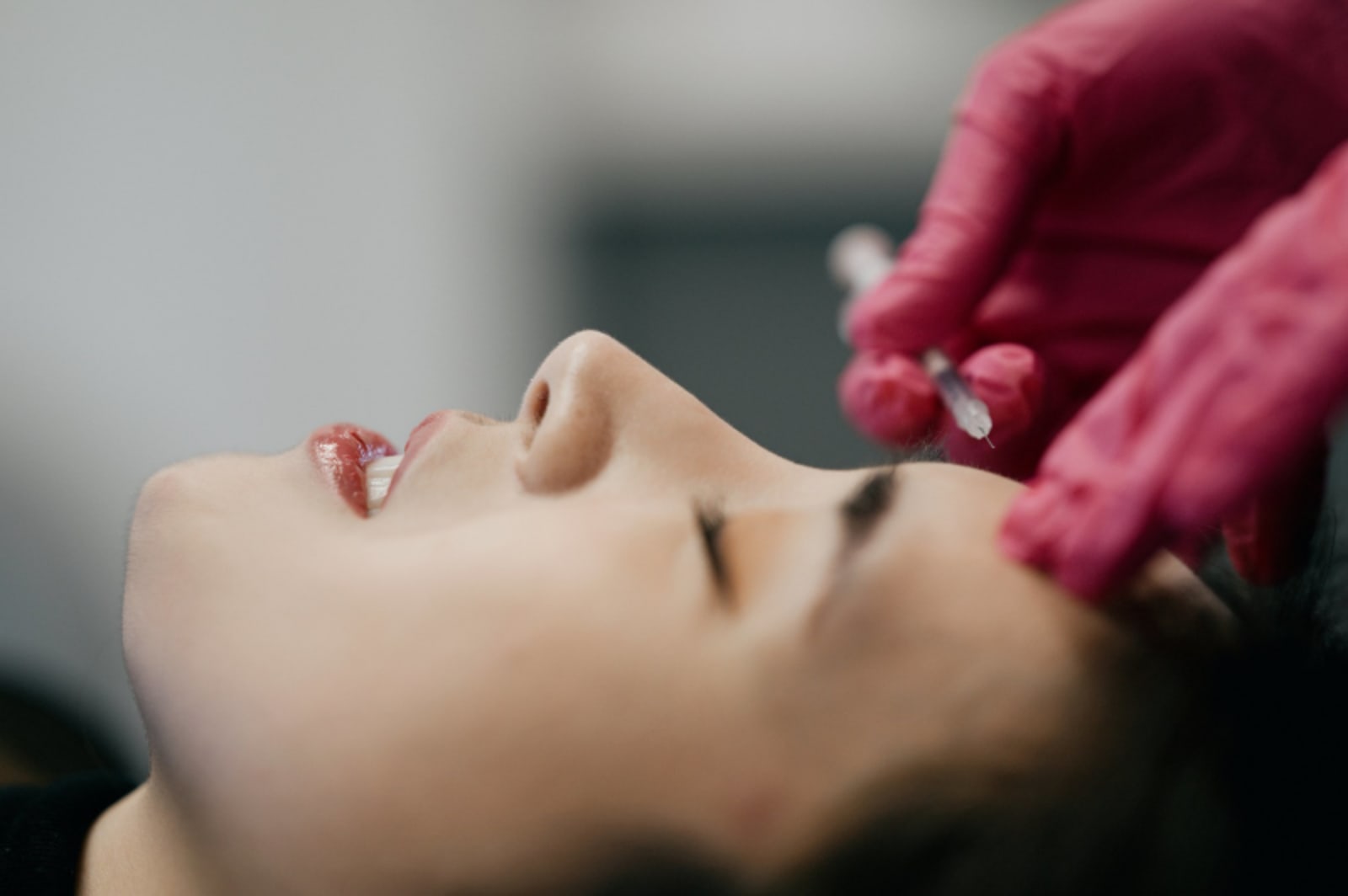 Patient receiving cosmetic dental treatment with pink bib in chair