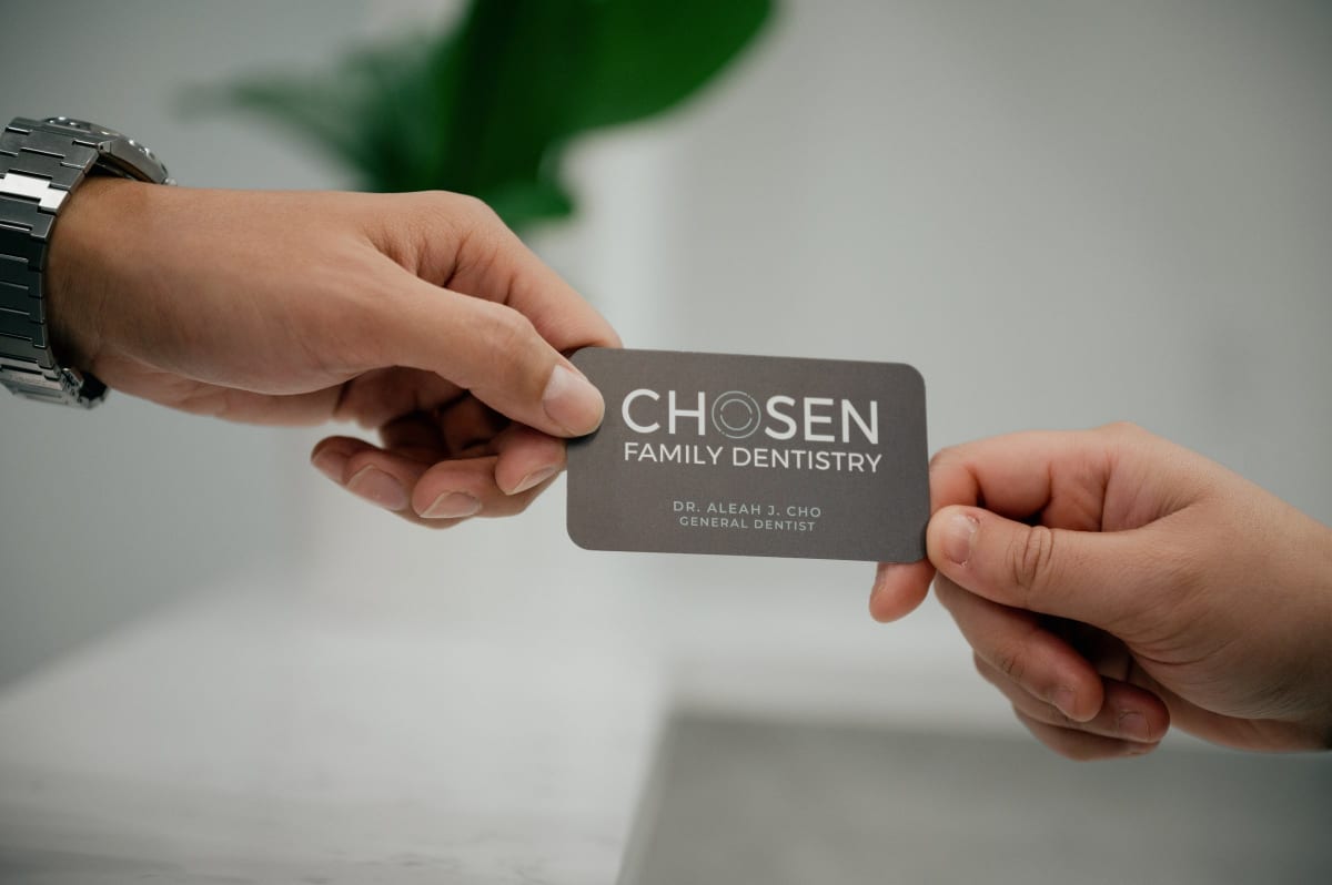 Close-up of hands exchanging a dental veneer shade guide card