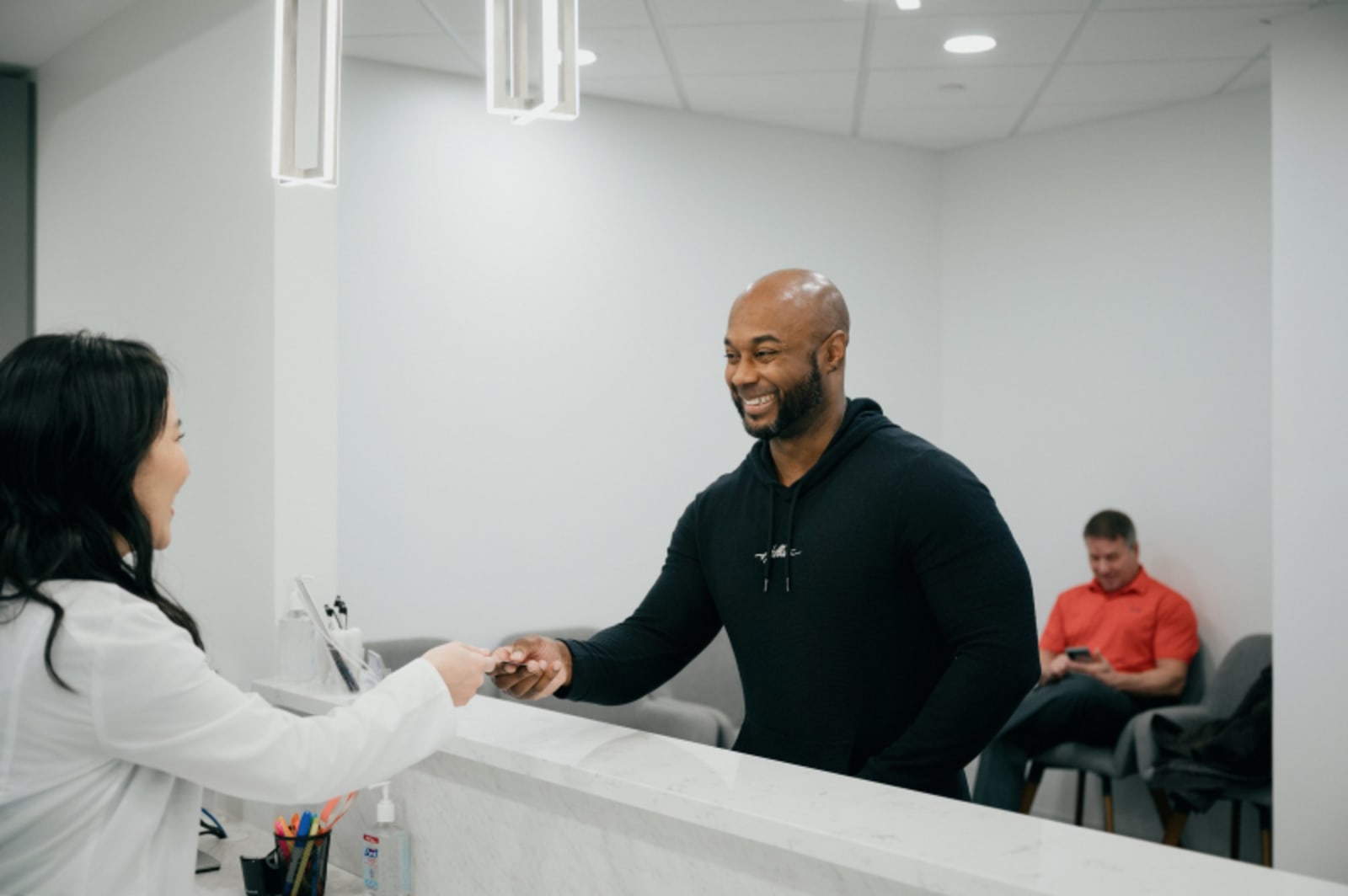 Male dentist consulting with female patient at reception desk
