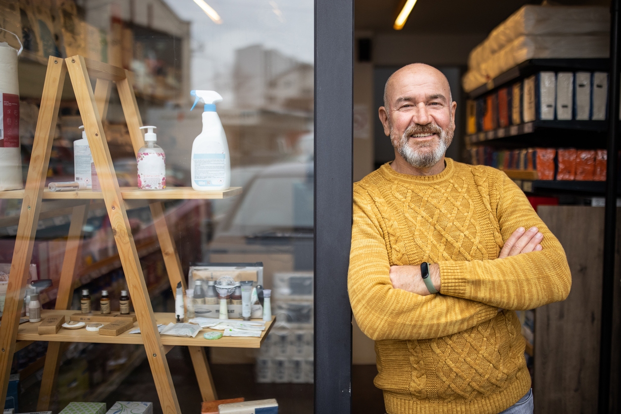 Small business owner leaning on door frame smiling after accessing Bizcap's Line of credit ultra