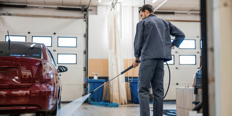 Car wash business owner cleaning car smiling after securing a Bizcap business loan