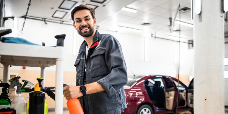 Car wash business owner cleaning car smiling after securing a Bizcap business loan
