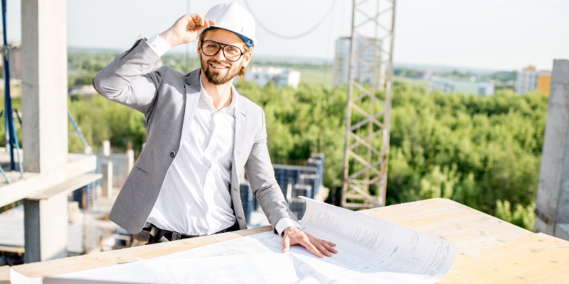 Property developer standing in the middle of construction site holding papers