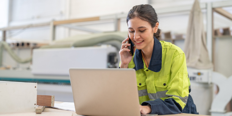 Infrastructure engineer smiling looking at computer surrounded by equipment