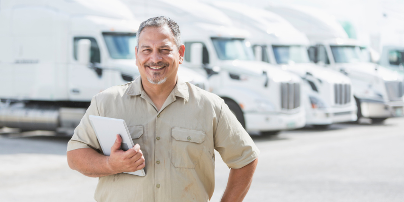 Man who runs a transport company standing in front of trucks