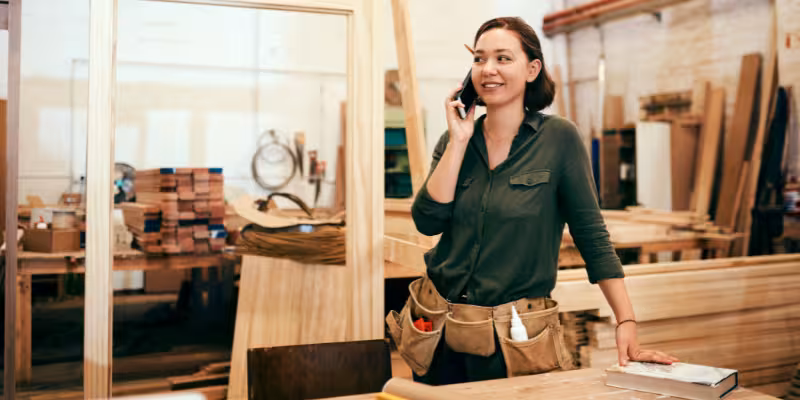 Woman carpenter talking on phone to her broker about recent payday superannuation changes