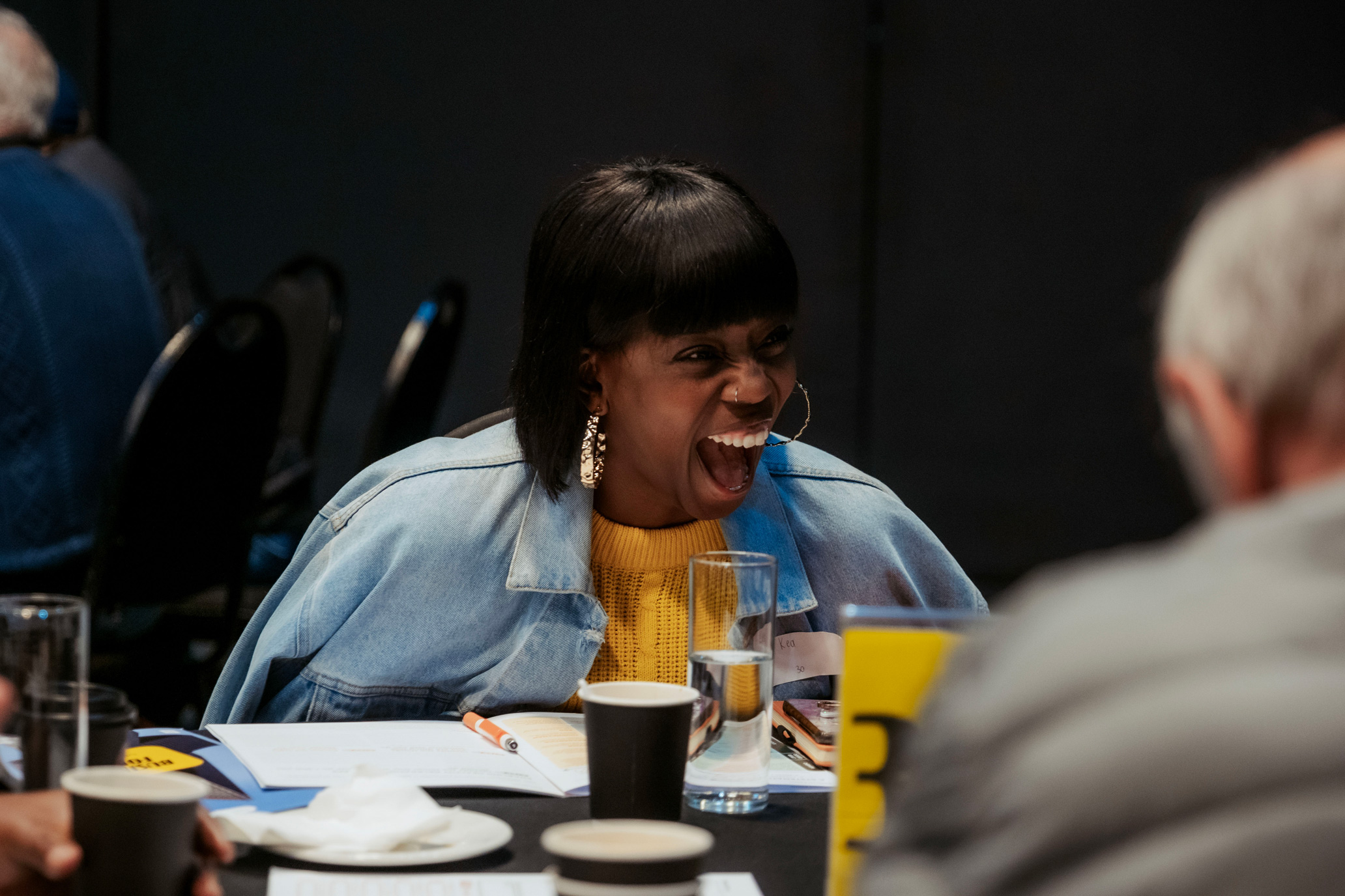 Woman laughing in joy with her table at a restory business breakfast session discussion.
