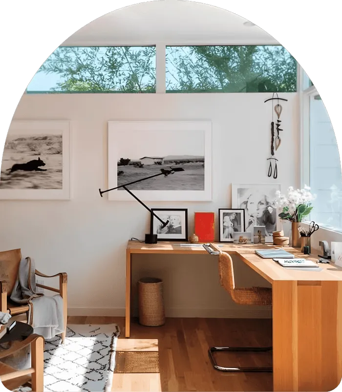 A room with a desk, chair and pictures on the wall.