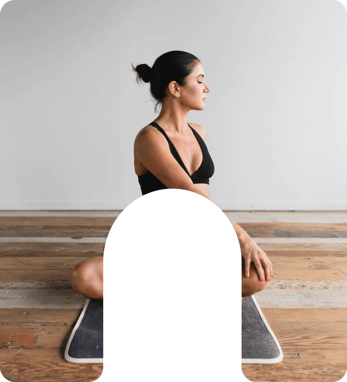 A woman sitting on a mat with her legs crossed.