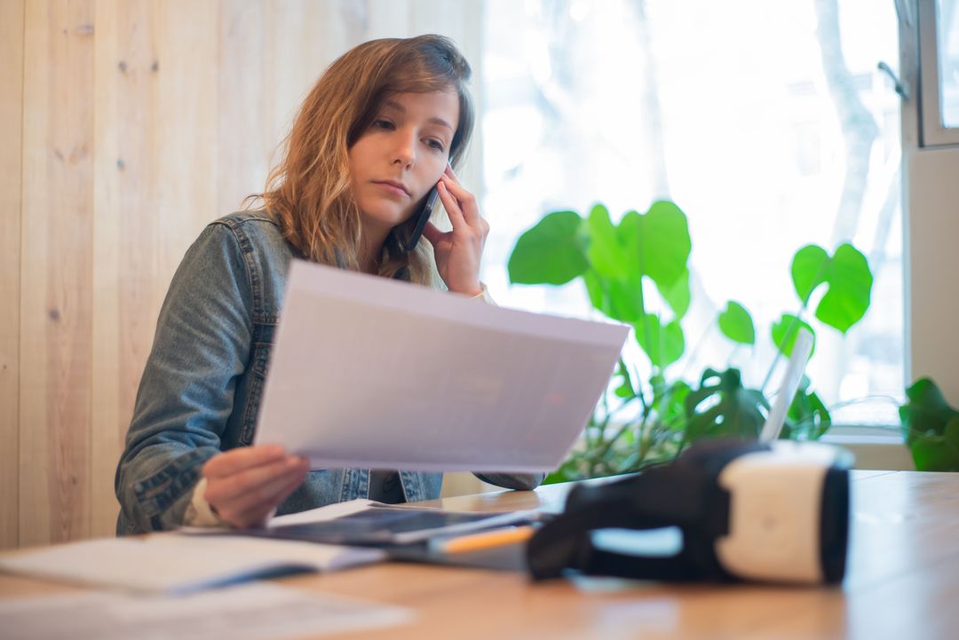 A manager reading a report at a desk while speaking on the phone