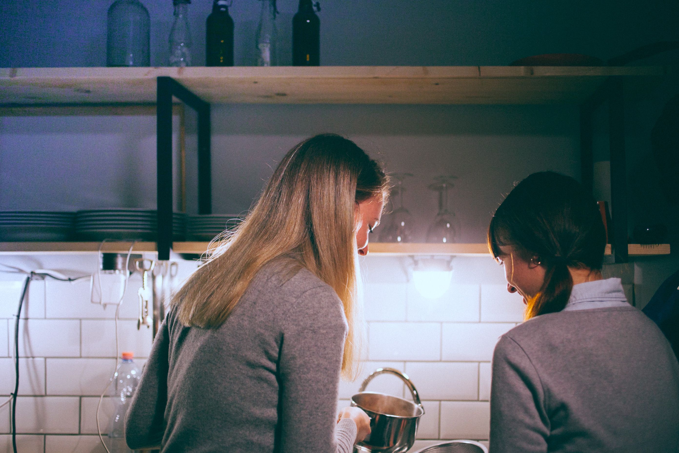 Two people standing side by side at a kitchen worktop, seen from behind
