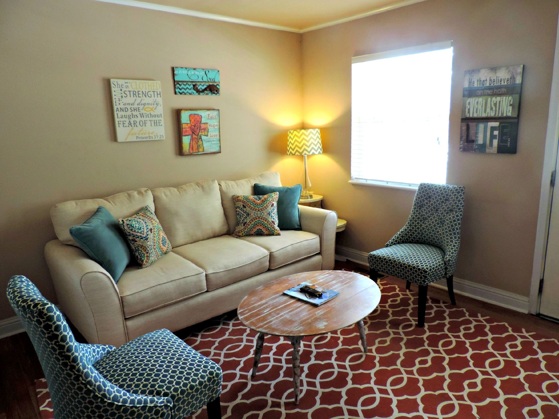 An empty domestic living room with a sofa, two armchairs, a lamp and a coffee table