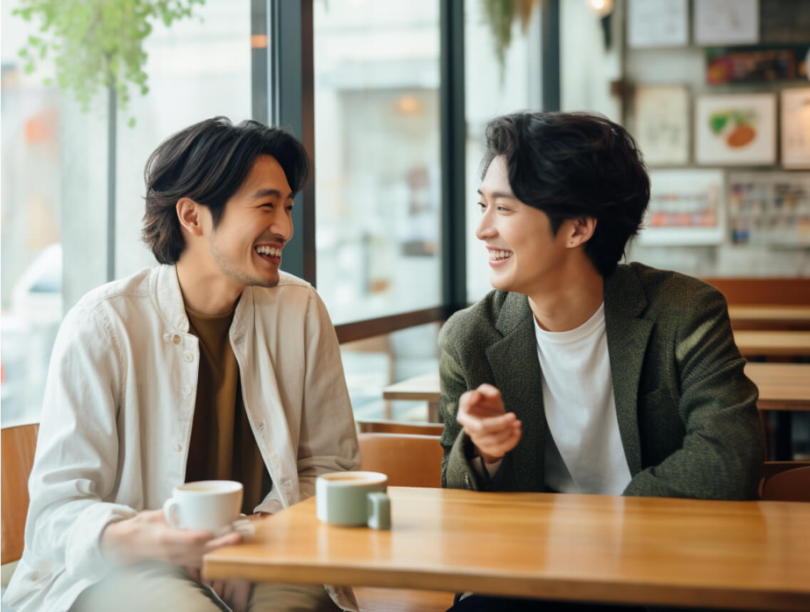 Two men enjoying a cup of coffee in a cozy cafe, sitting at a table and engaged in conversation.