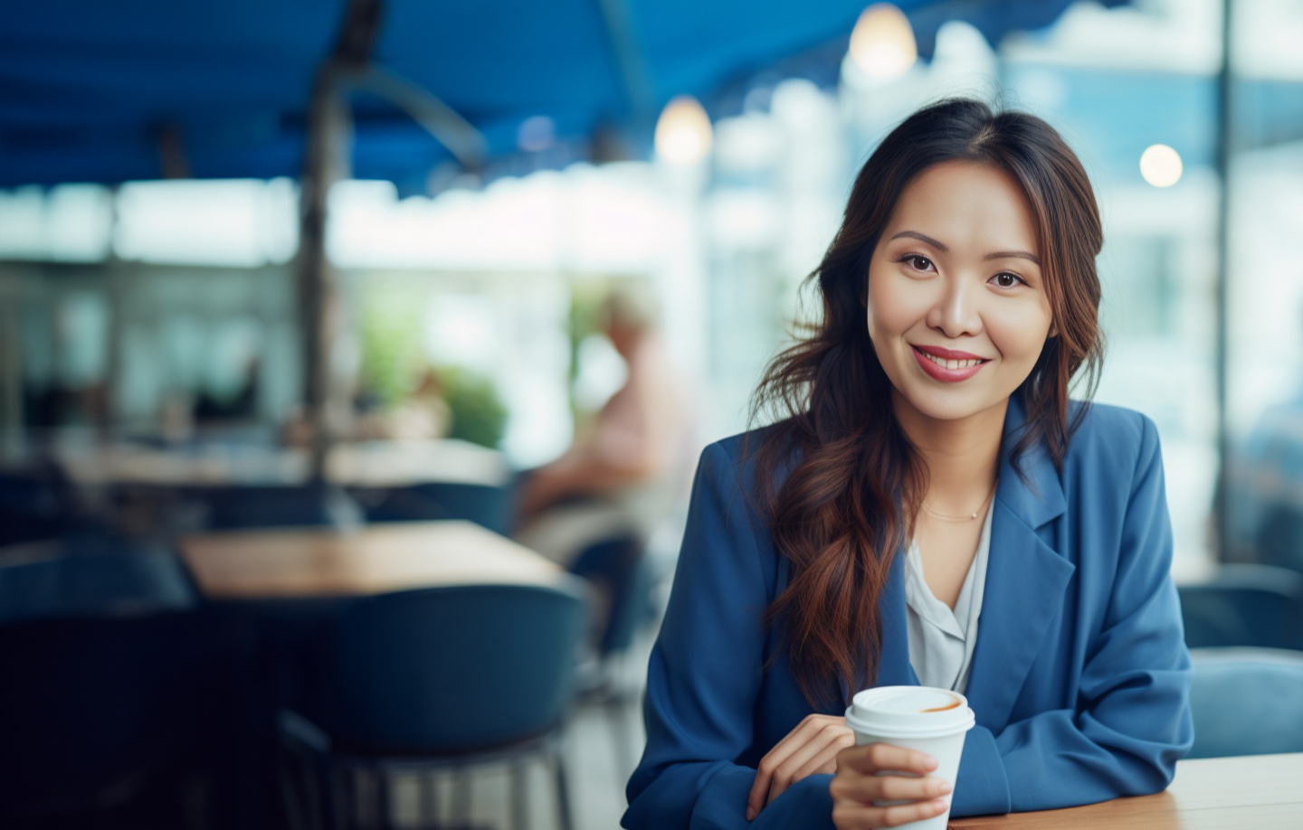 A smiling Asian woman enjoying a cup of coffee in a cozy cafe.