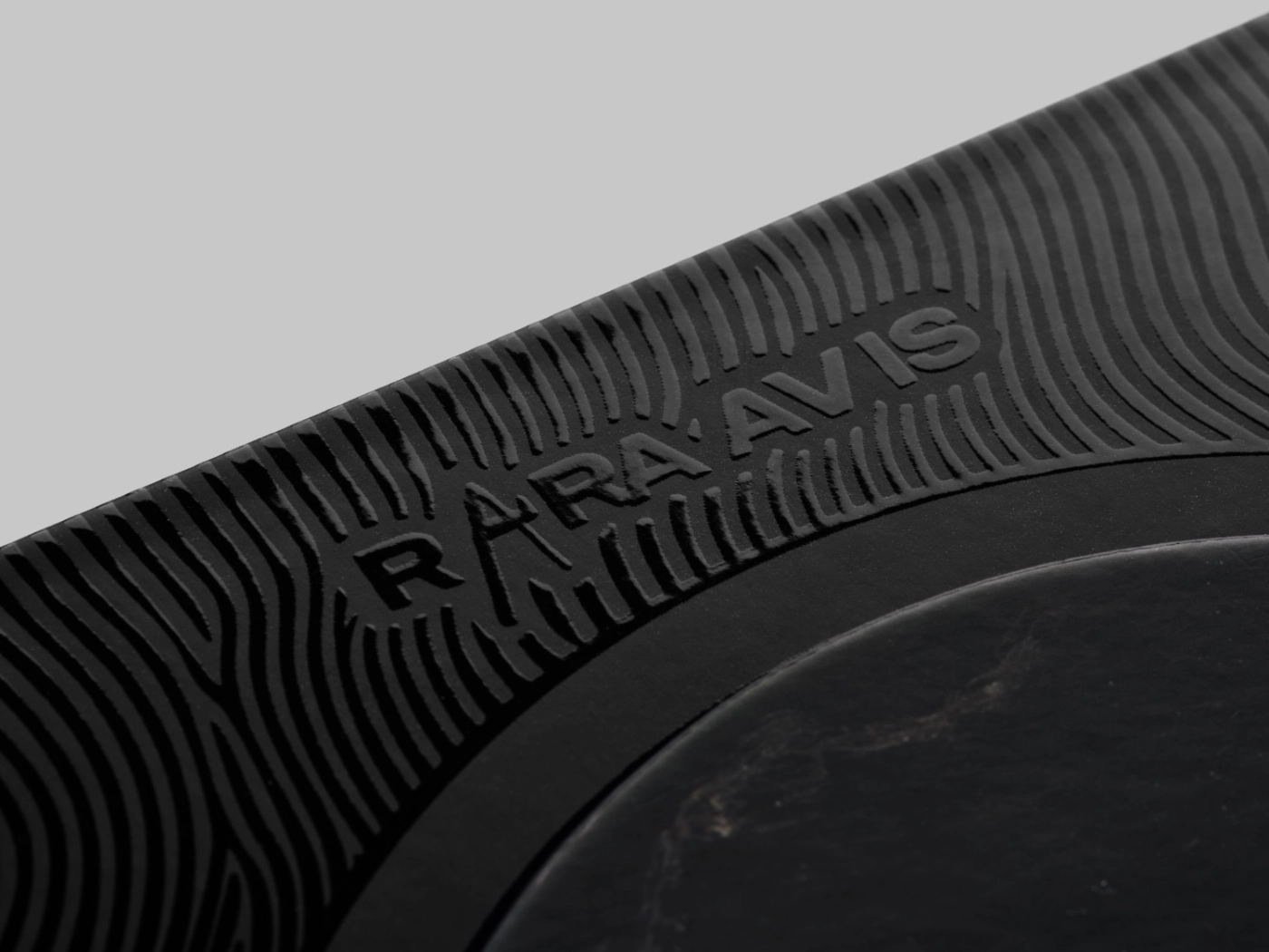 Detalle del packaging de RARA AVIS con barniz UVI selectivo de alto relieve que crea ondas brillantes sobre una superficie mate.