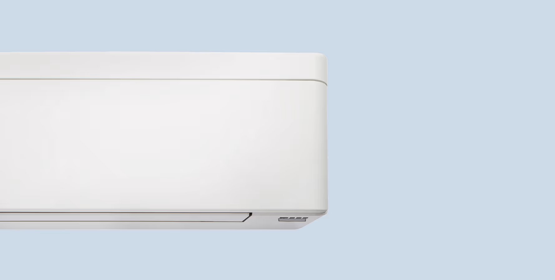 Close-up van een strak vormgegeven wandmodel airconditioner tegen een lichtblauwe achtergrond.