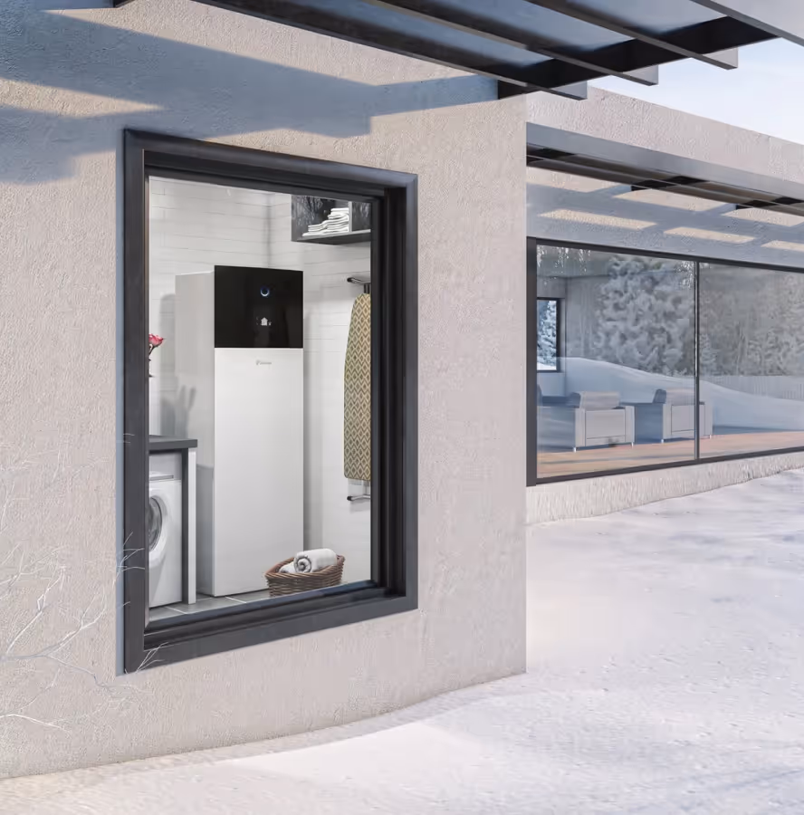 Bodem warmtepomp binnen opgesteld in een bijkeuken met zicht op een moderne woning