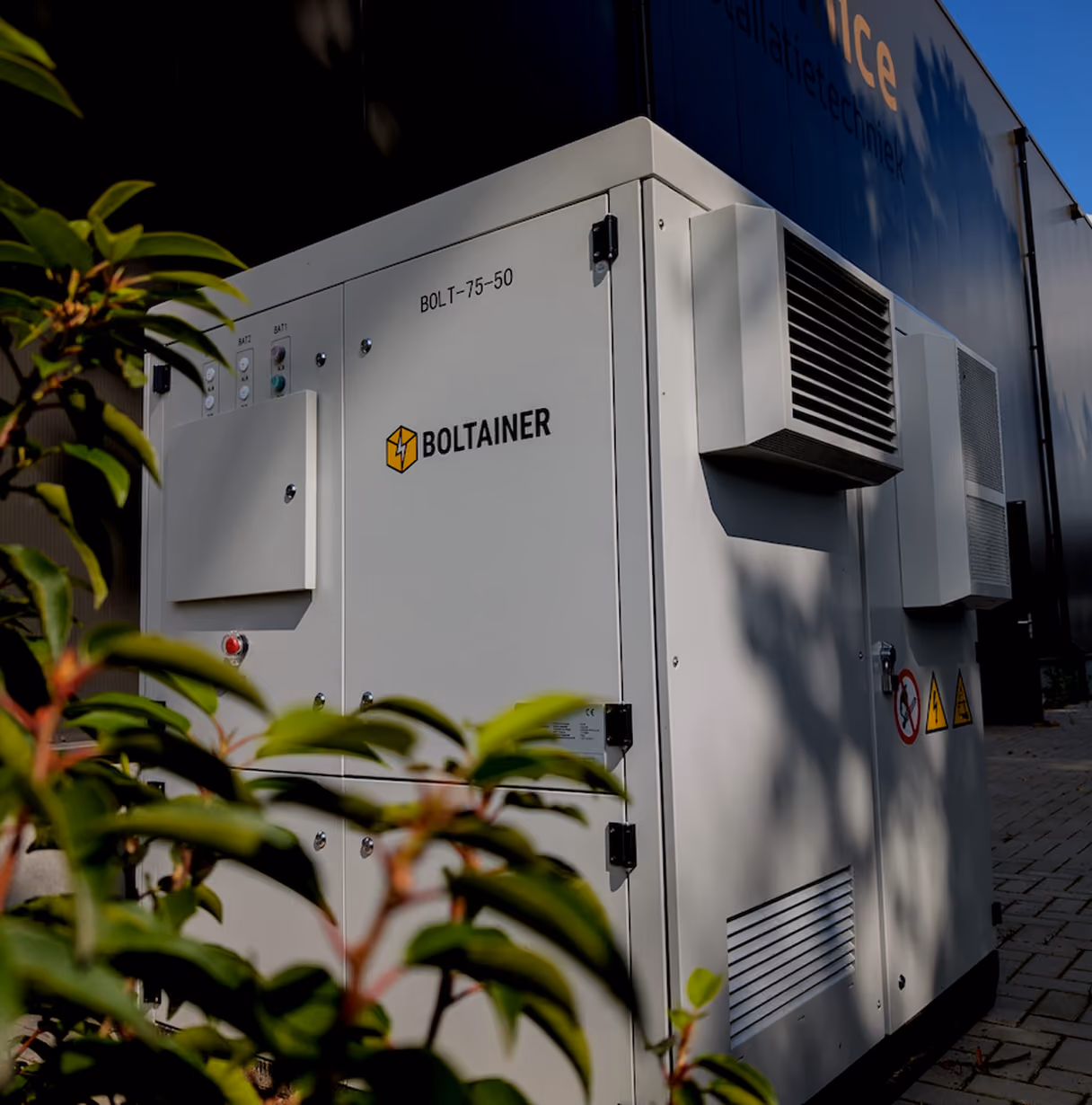 Witte Boltainer BOLT-75-50 batterijcontainer voor energieopslag naast een bedrijfspand