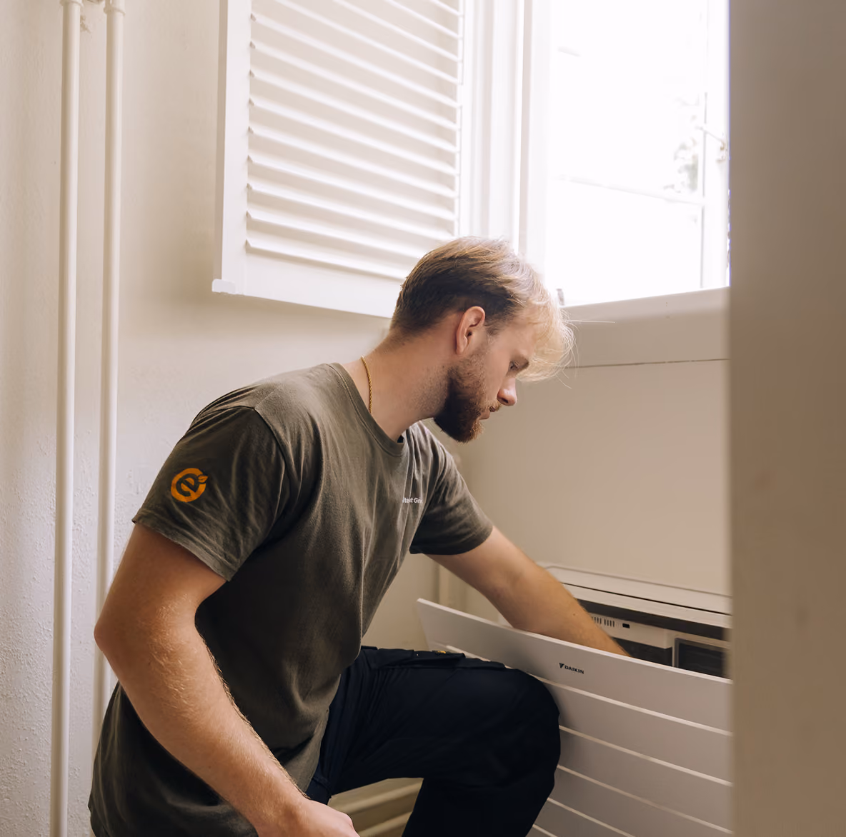 Monteur van Elite Klimaat Groep plaatst het frontpaneel op een Daikin airco binnendeel onder een raam