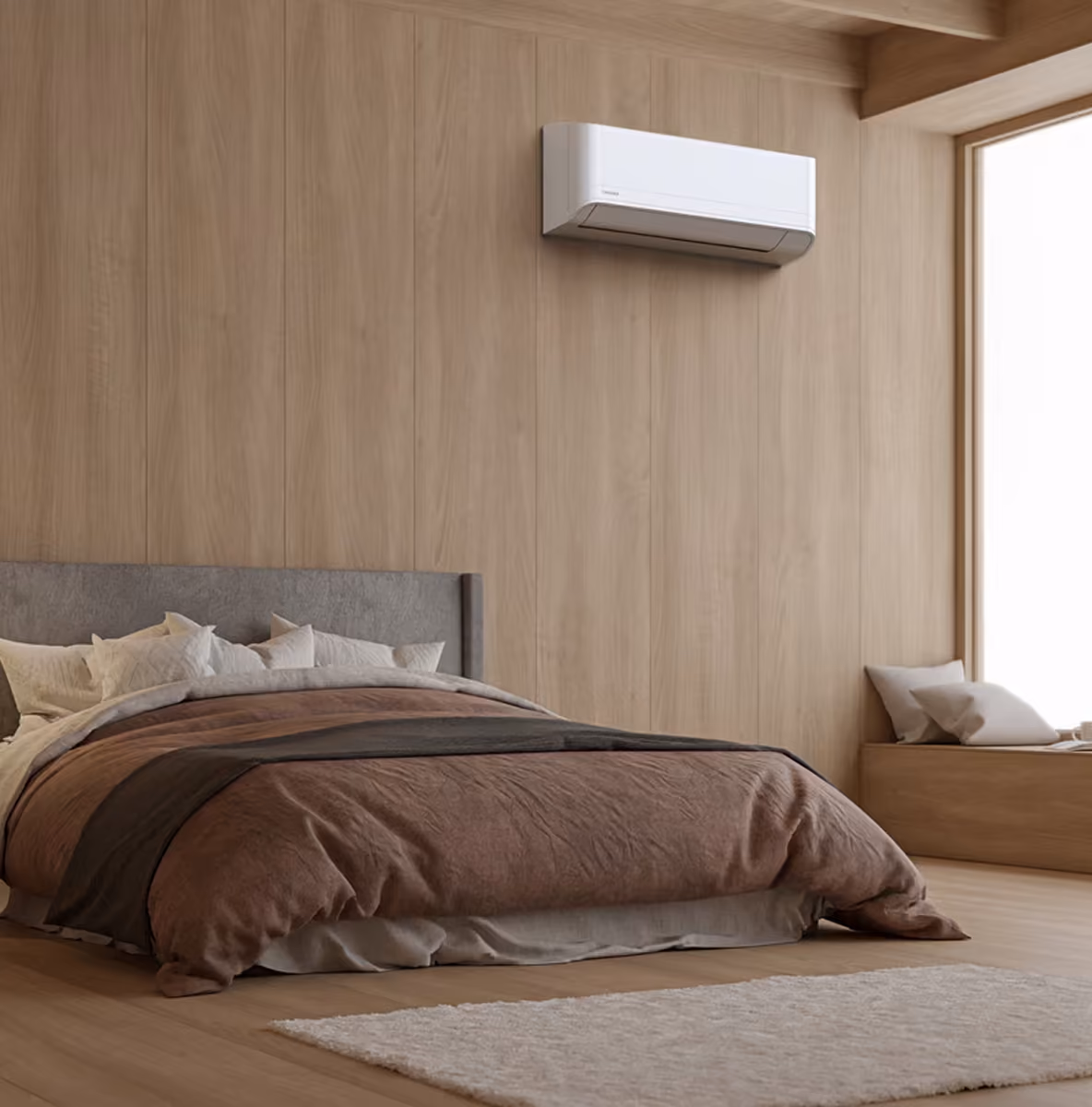 Toshiba wandmodel airco op een houten lambriseringswand in een slaapkamer met bruin beddengoed