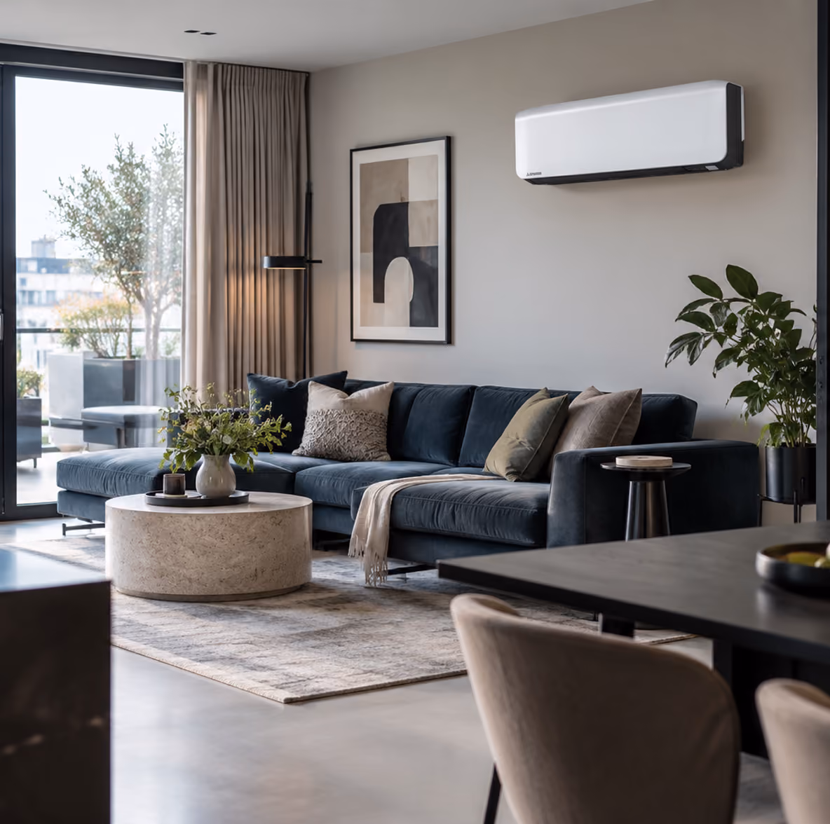 Mitsubishi standaard wandmodel airco in een lichte woonkamer met blauwe velours bank en ronde travertin salontafel
