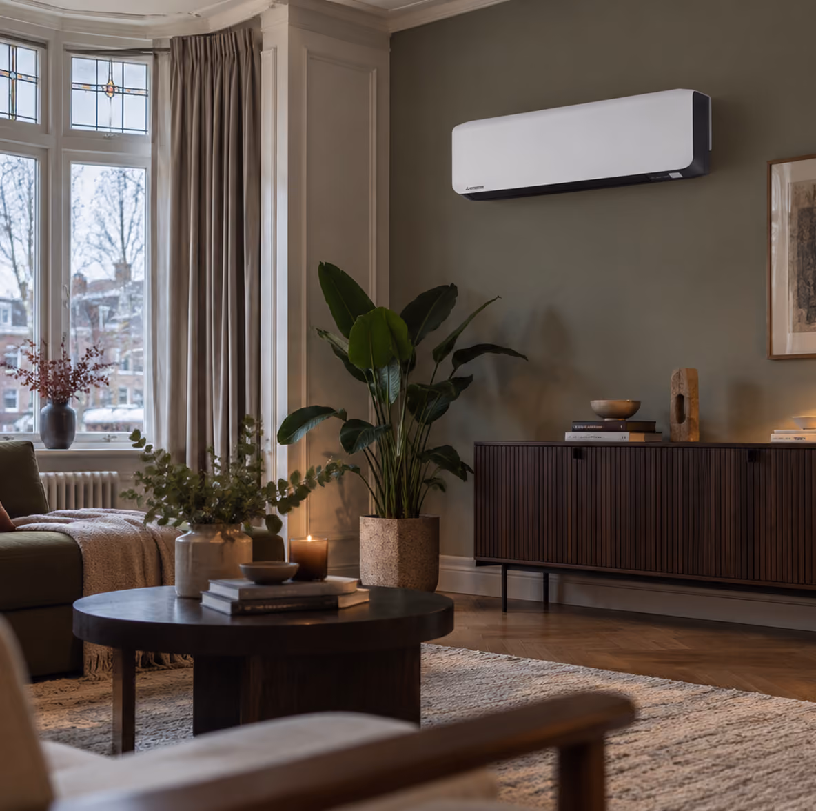 Mitsubishi Diamond Series airco op een olijfgroene wand in een klassieke woonkamer met erker en kaarslicht in de winter