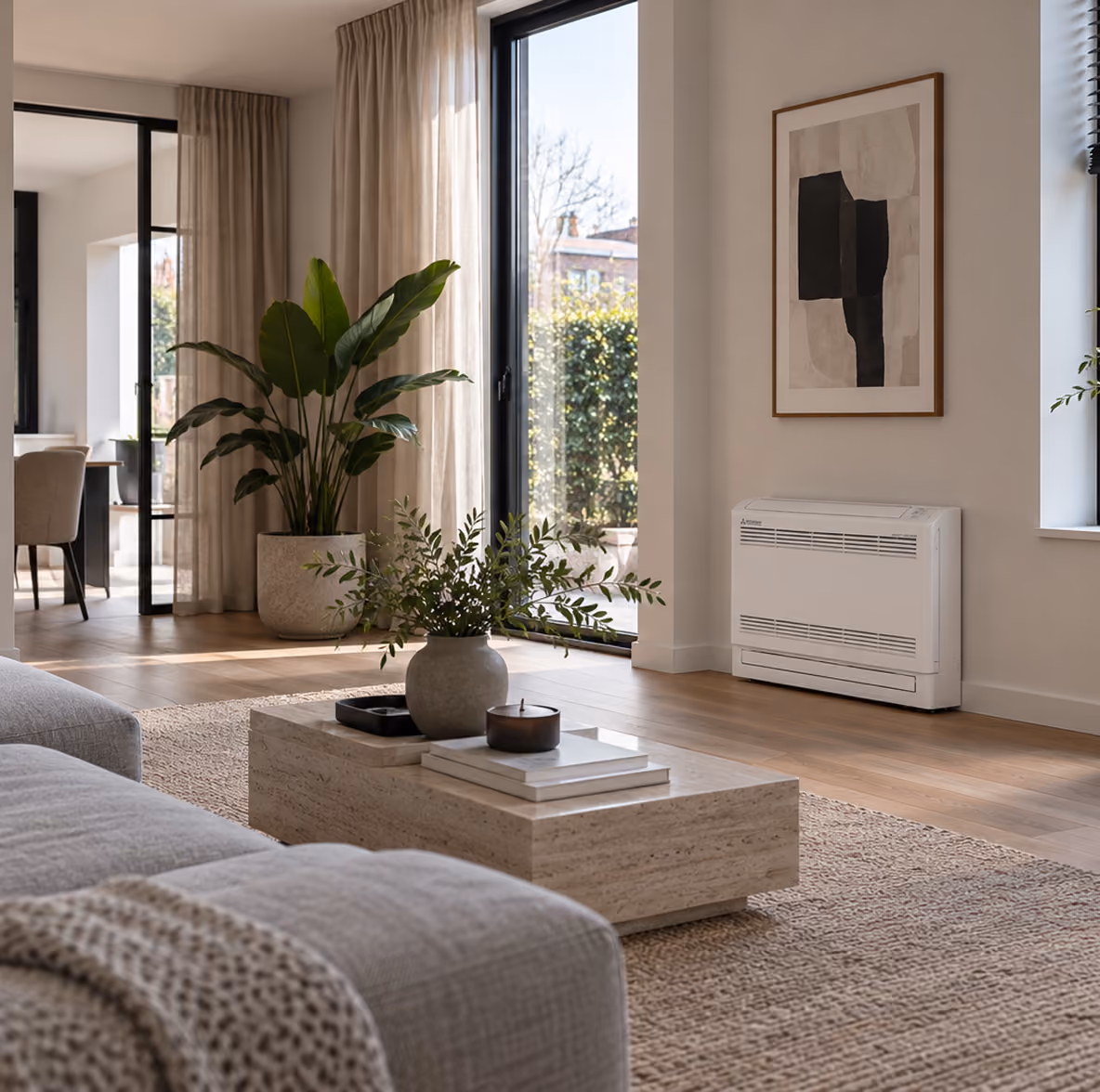 Mitsubishi vloermodel airco laag aan de wand in een lichte woonkamer met travertin salontafel en tuindeuren