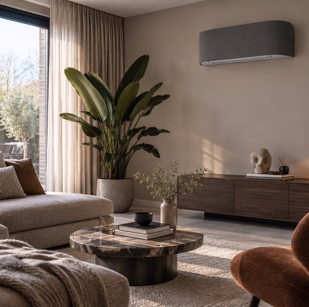 Toshiba Haori airco met grijs stoffen front op een zandkleurige wand in een woonkamer met marmeren salontafel en grote plant
