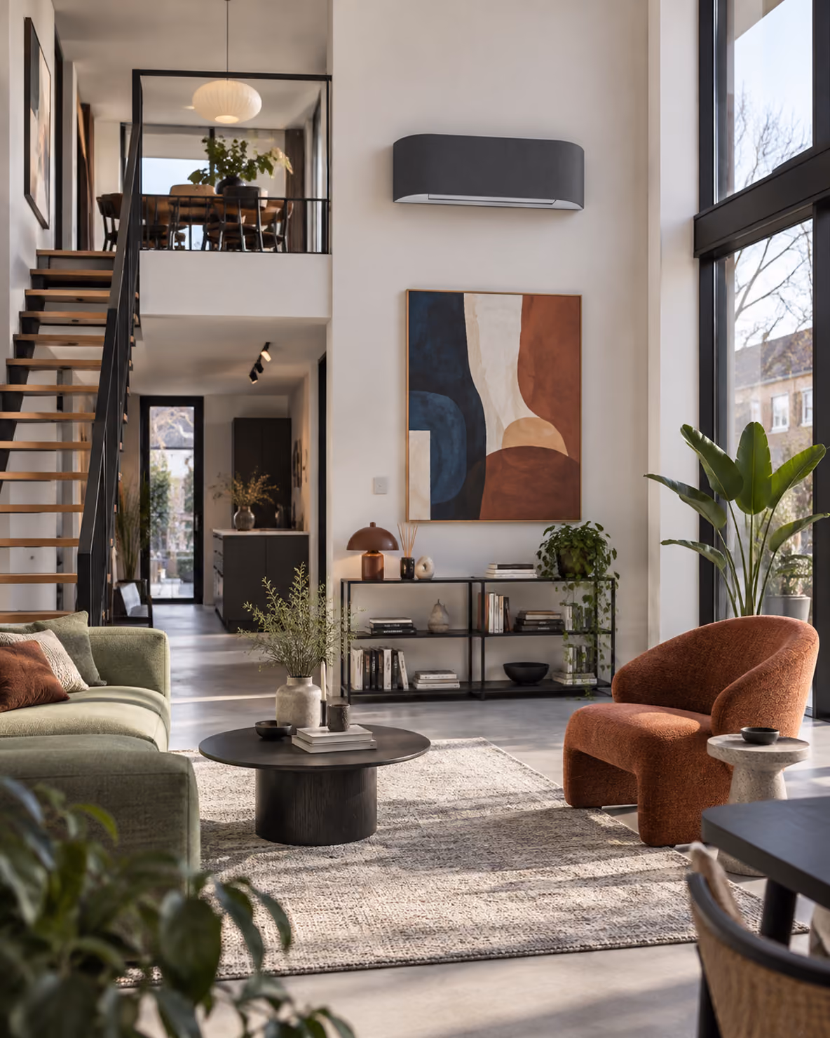 Toshiba Haori airco met donkergrijs stoffen front in een loft met vide, abstract schilderij en terracotta fauteuil