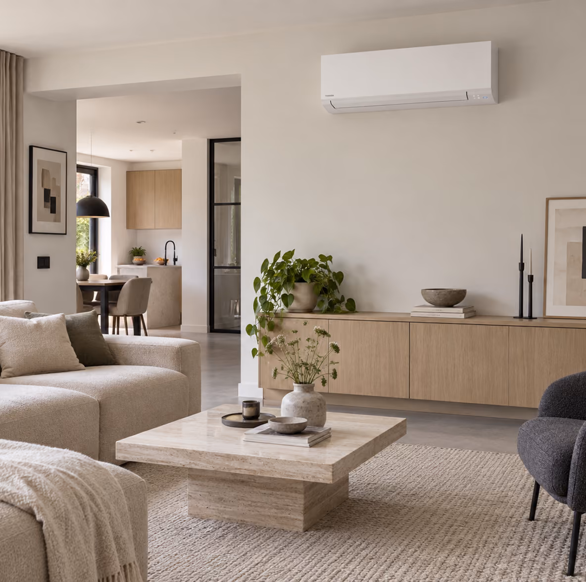 Toshiba Kazumi airco boven een eiken dressoir in een lichte woonkamer met travertin salontafel en open keuken
