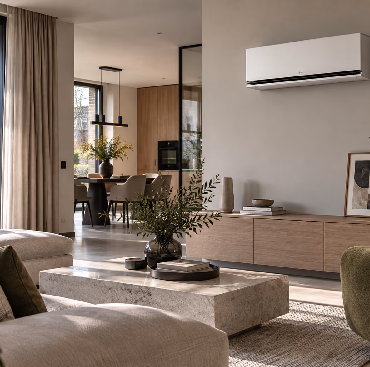 LG AI Air airco boven een eikenhouten tv-meubel in een lichte woonkamer met open keuken