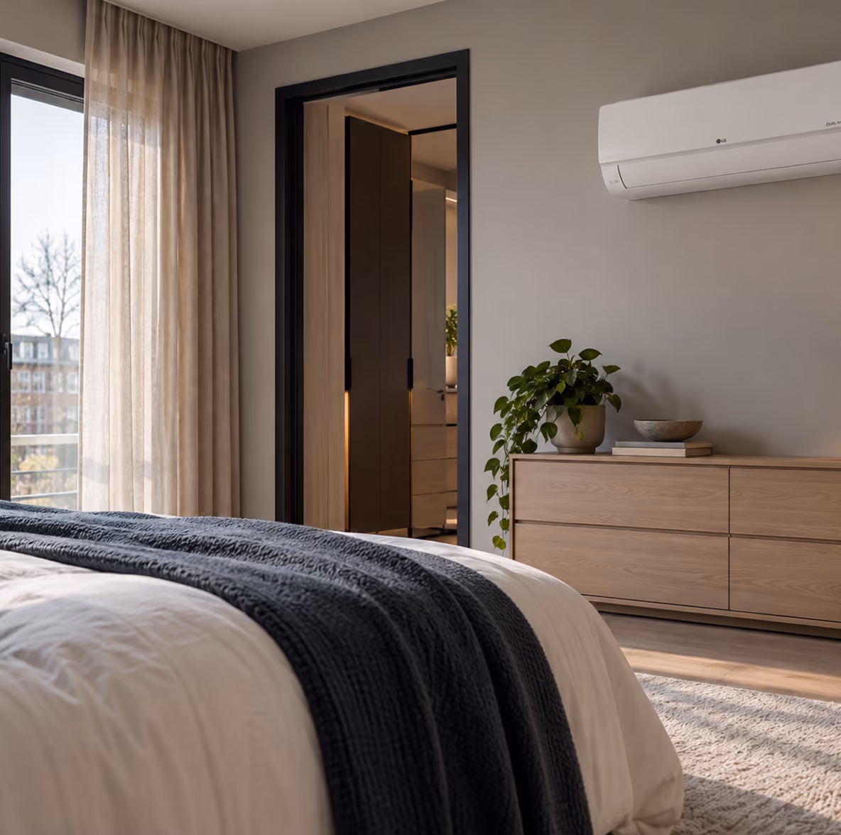 LG Standard Plus airco boven een eiken ladekast in een zonnige slaapkamer met inloopkast