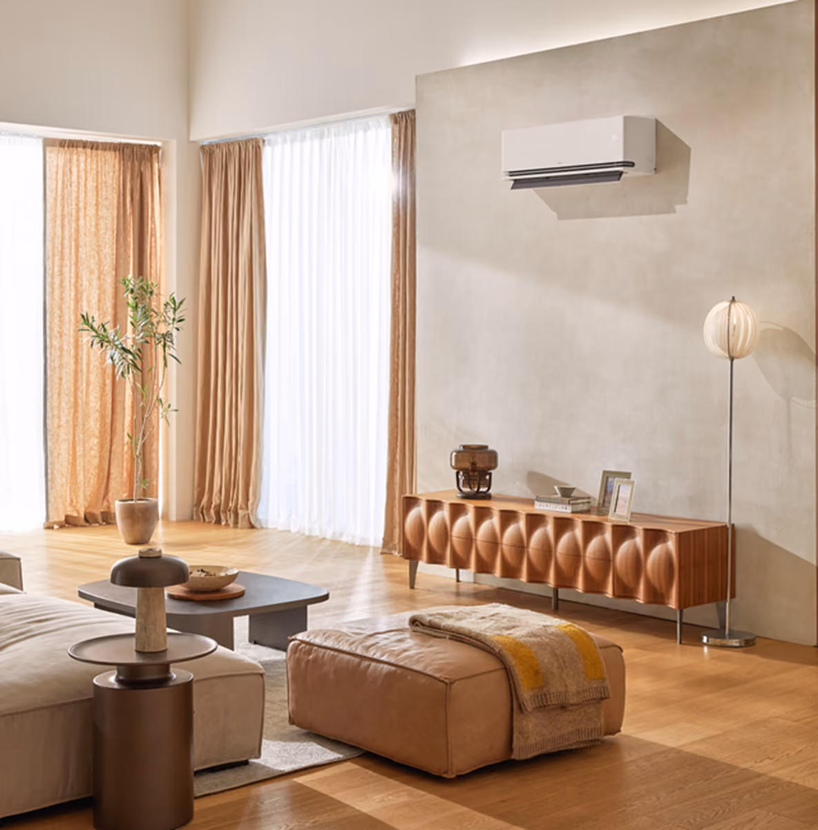 Wit LG wandmodel airco hoog aan de muur in een woonkamer met houten vloer en zandkleurige bank