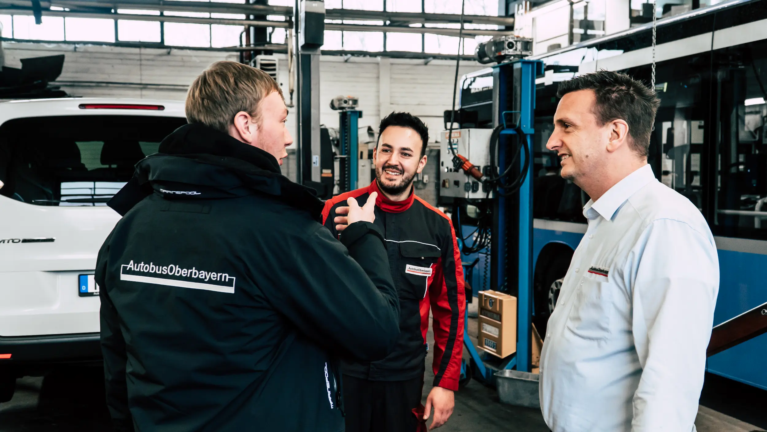 Three workers talking to each other surrounded by tools and equipment for transport vehicles maintenance and repair.