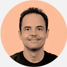 Retrato de un hombre sonriente con camiseta negra sobre fondo blanco.