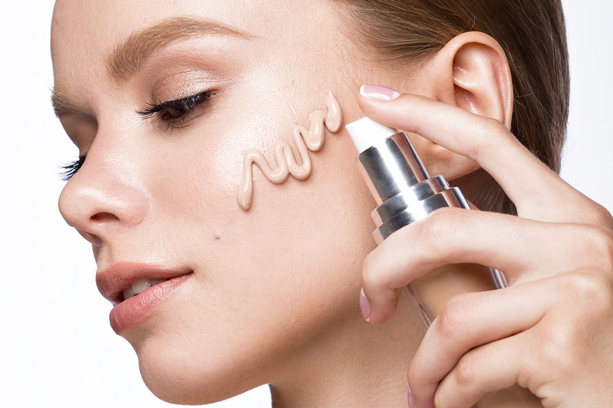 Young bride applying best primer for bridal makeup for a smooth base.