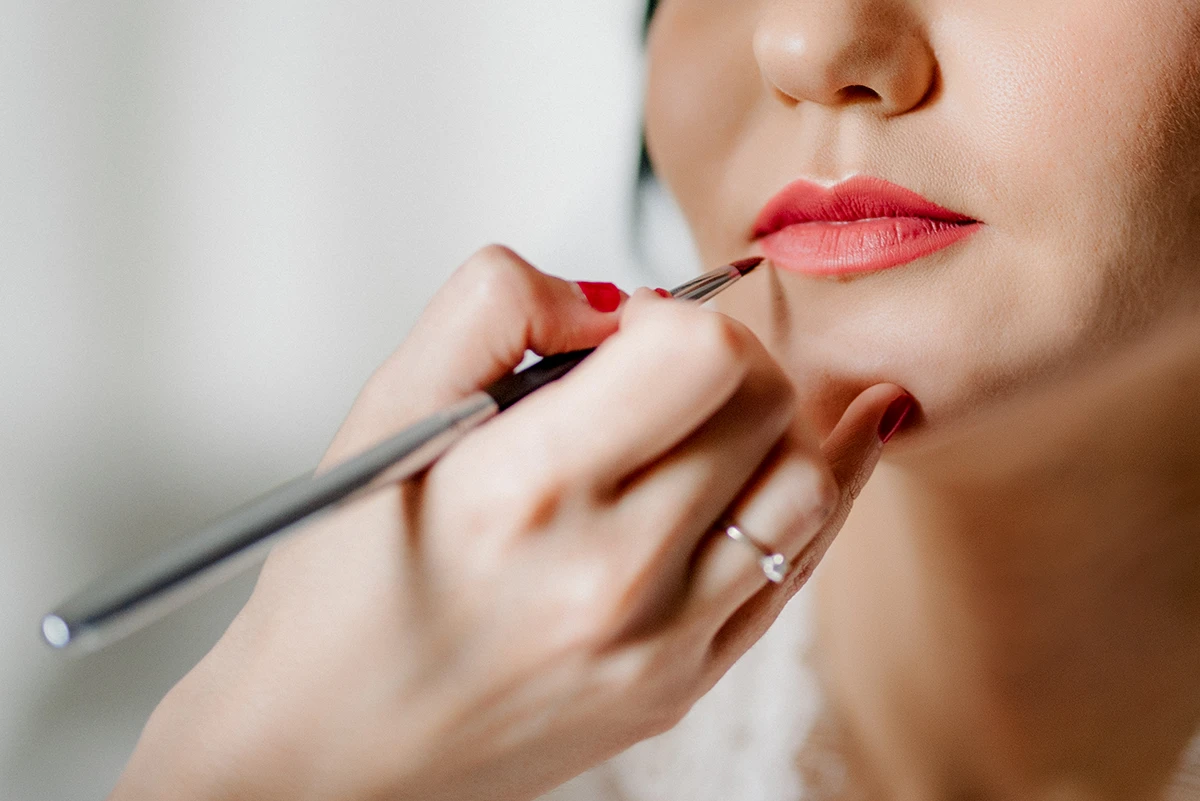 Bridal makeup session with makeup artist adding the best lip stain for wedding to complete the look.