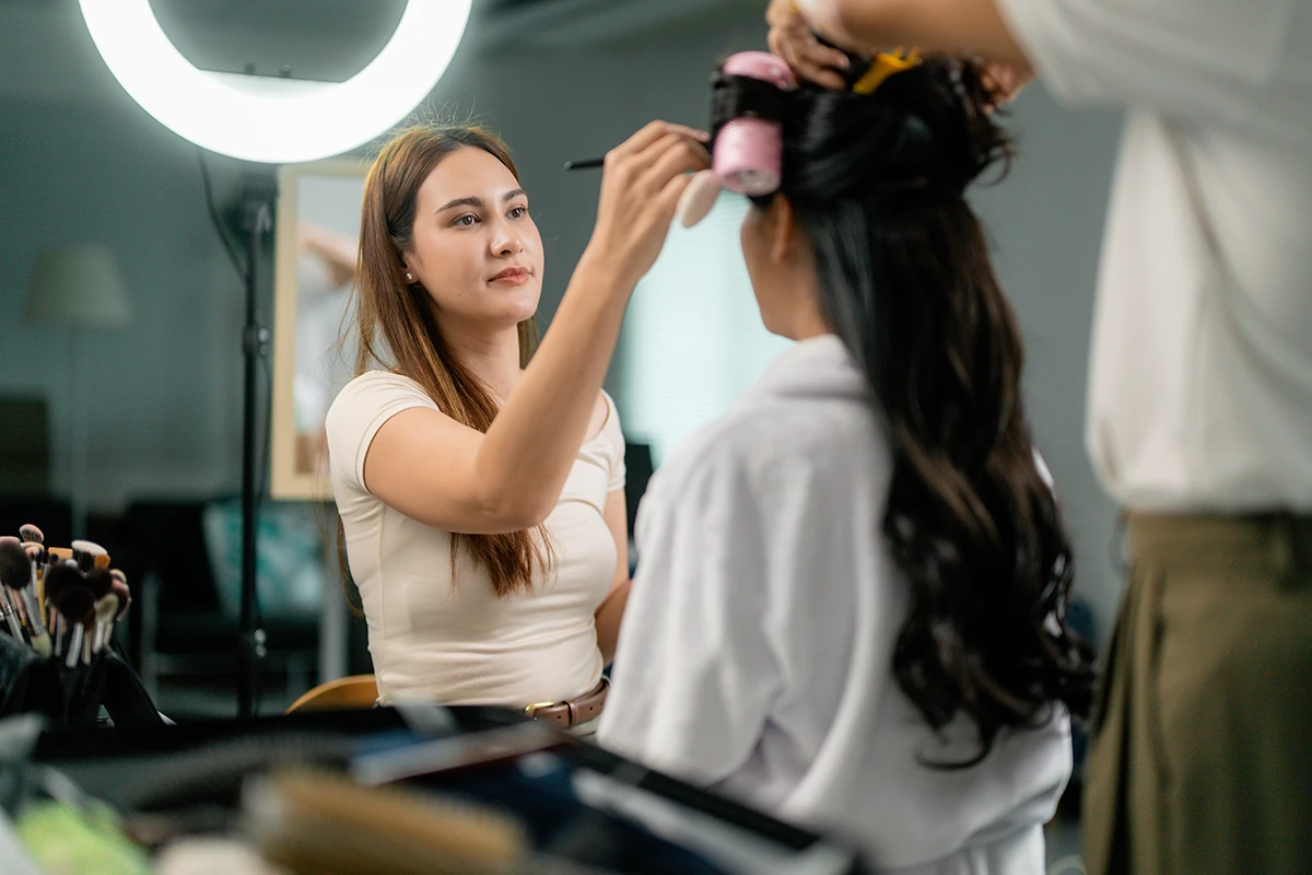 Bride getting makeup applied by bridal makeup artist for wedding trial.